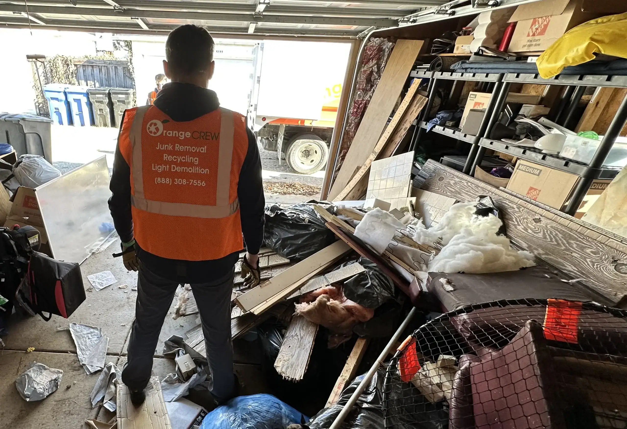 orange crew technician looking at the pile of garbage in the garage